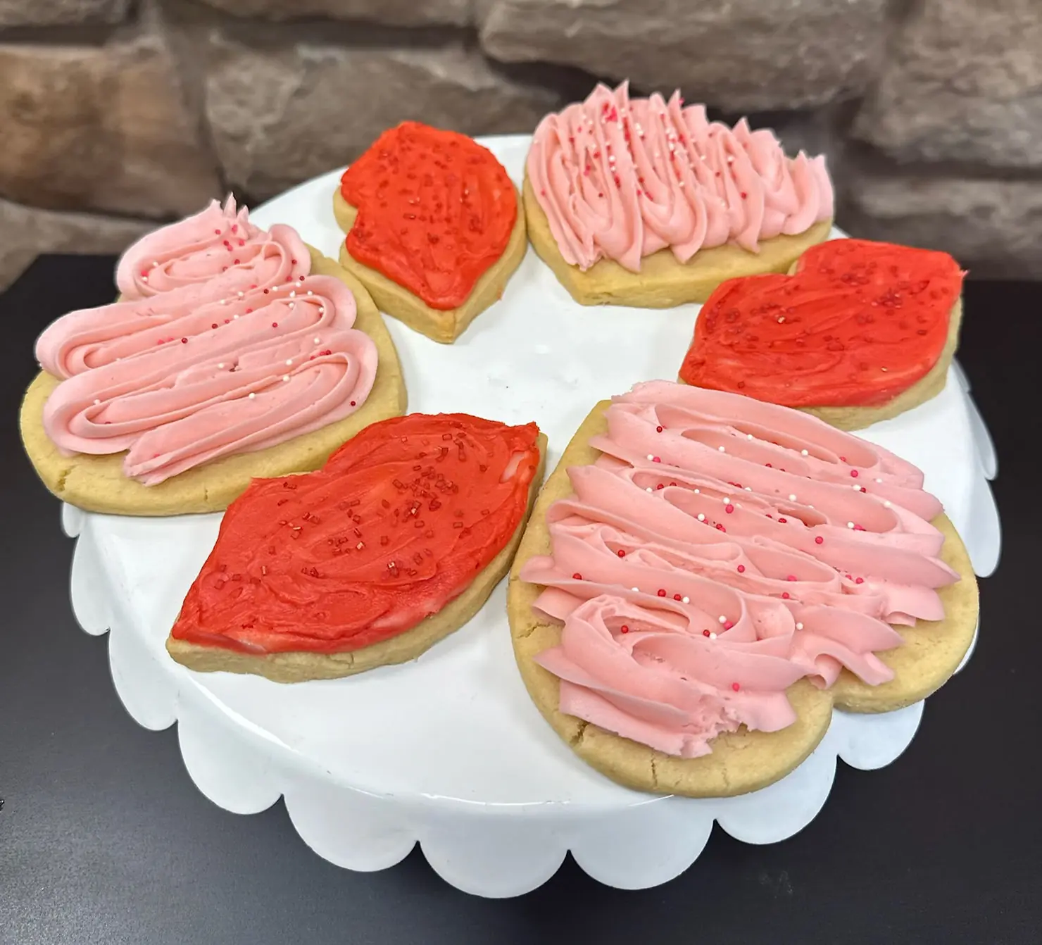 Eye-level view of a decorated sugar cookie shaped like a heart with pink and red icing